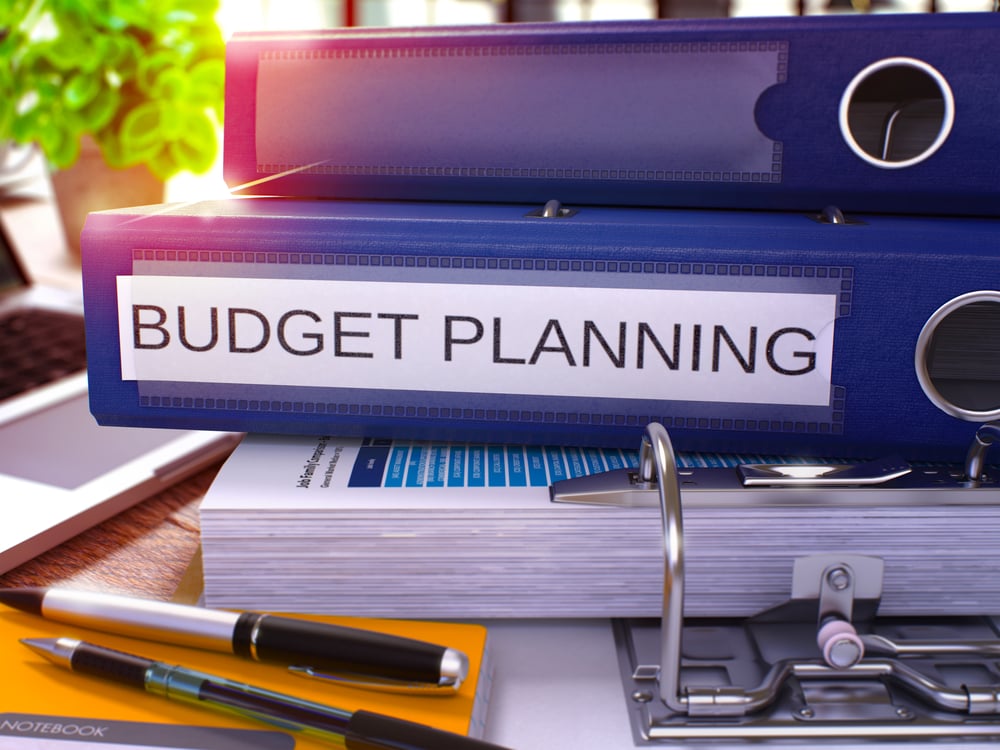 Blauer Aktenordner mit der Aufschrift "Budget Planning" auf einem Schreibtisch. Konzeptbild