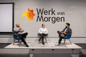 Ardal Toprak, Alicia Biewald und Deniz Sirmasac sitzen vor einer weißen Wand mit dem Werk von Morgen Logo